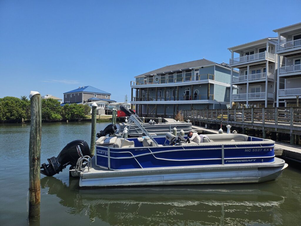 Blue pontoon boat docked at coastal marina with waterfront building — 4th of July in Surf City NC
