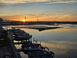 Stunning golden sunset over a calm marina waterway with boats docked along a wooden pier at Marina Joe's, the perfect way to end the perfect day at Marina Joe's