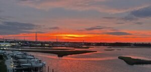 Waterfront dining at Marina Joe's — dramatic red and orange sunset over the docks, boats, and Intracoastal waterway in Surf City, NC