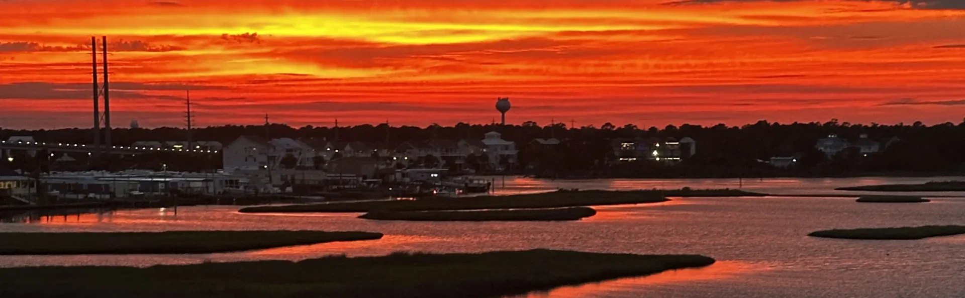 Golden hour Intracoastal Waterway sunset with orange sky reflecting on calm water and dark marsh islands.