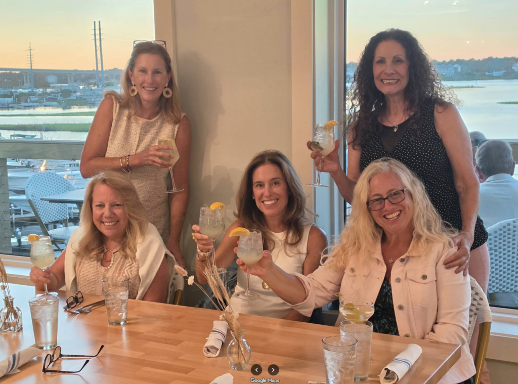 Guests enjoying drinks together beside the waterfront windows at Marina Joe’s